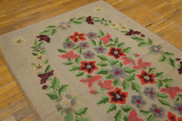 Low-pile beige rug with a colorful floral garland design rests on distressed wooden floorboards.