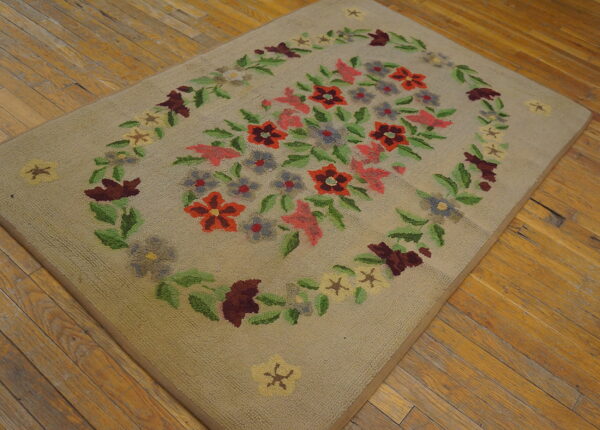 Tan low-pile rug with red, pink, and green floral cluster design on distressed wood floors.