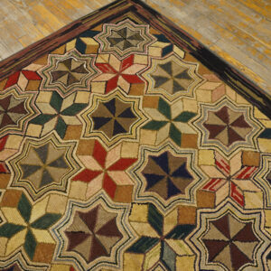 A highly textured rug featuring repeating red, green, and brown star patterns on distressed wood flooring.
