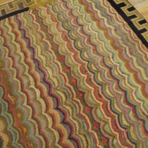 Low-pile rug with wavy multicolor stripes and a black and gold Greek key border on wood.