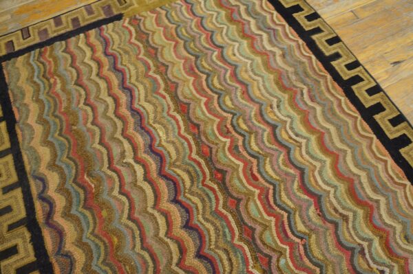 Low-pile rug with wavy multicolor stripes and a black and gold greek key border on wood.