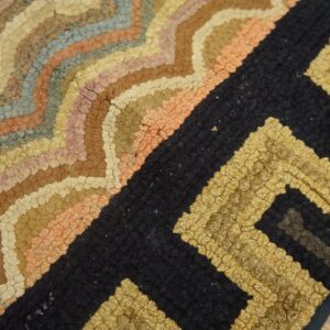 Textured rug with multicolored curved bands transitioning into a chunky black and gold geometric pattern.