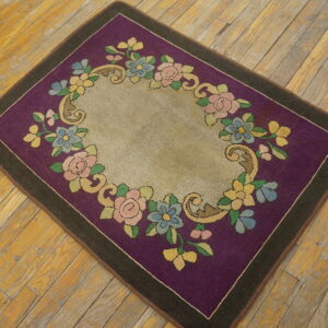Purple and beige low-pile rug featuring a colorful floral garland border on rustic wood floors.