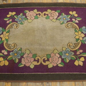 A hooked rug with a purple field, dark border, and floral motifs surrounding a central beige oval.