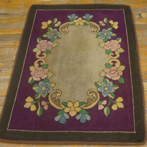 Low-pile purple rug with a beige center and colorful floral garland on distressed wood.