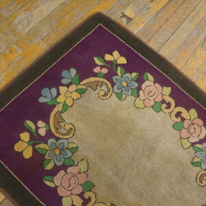 Colorful floral pattern on a looped purple and tan rug resting on distressed yellow wood flooring.