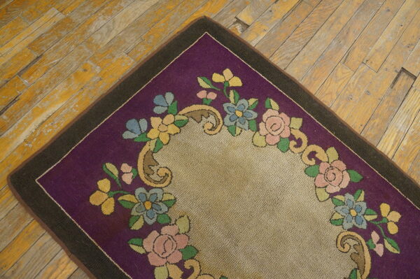 Colorful floral pattern on a looped purple and tan rug resting on distressed yellow wood flooring.