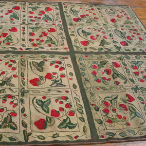 Low-pile rug with red strawberry and green leaf motifs in framed panels lies on wood flooring.