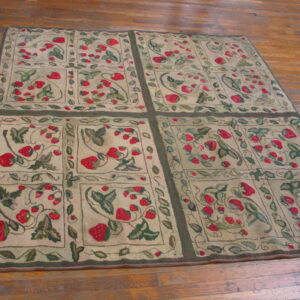 Beige rug featuring a detailed red strawberry and green leaf pattern framed by dark borders on wood floor.