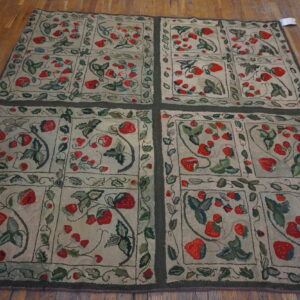Hooked rug featuring red strawberry motifs and green vines in framed panels on hardwood flooring.
