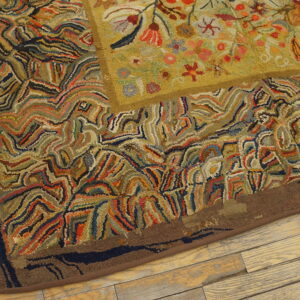 Textured hooked rug with an olive floral center and a wavy, multicolored abstract border on wood flooring.