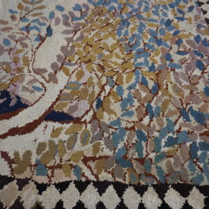 Textured loop pile rug featuring multicolored foliage and a dark diamond border on light brown wood flooring.