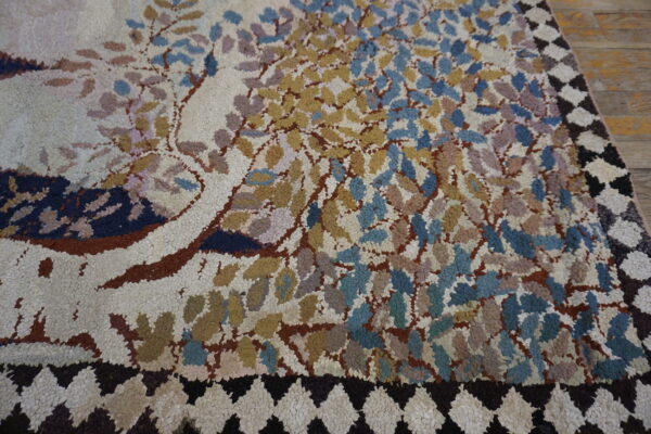 Textured loop pile rug featuring multicolored foliage and a dark diamond border on light brown wood flooring.