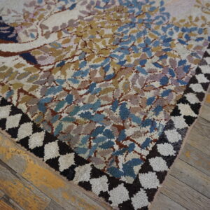 Chunky pile rug with a colorful nature pattern and dark zigzag border rests on weathered wood planks.