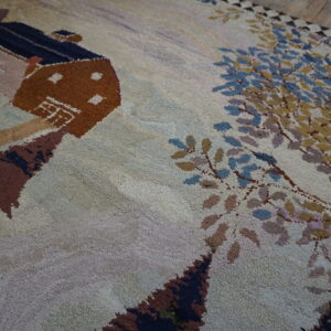 Textured high-pile rug featuring a pictorial design of a brown cabin and trees on rustic wood flooring.