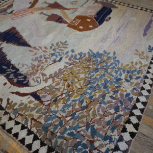 Cream high-pile rug with blue, gold, and brown abstract foliage and building designs on wood flooring.