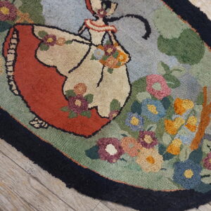 A multicolored hooked rug depicting a dancing woman and flowers sits on light wood planks.