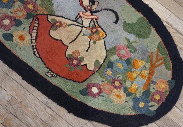 A multicolored hooked rug depicting a dancing woman and flowers sits on light wood planks.
