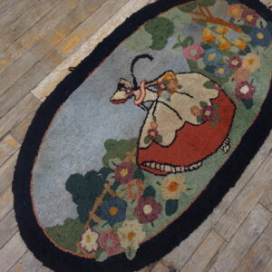 Oval hooked rug featuring a woman in a red dress surrounded by colorful floral motifs on gray wood.