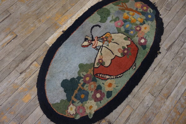 Oval hooked rug featuring a woman in a red dress surrounded by colorful floral motifs on gray wood.