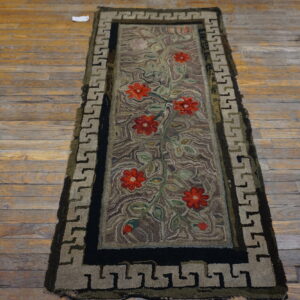 Textured runner with red florals, green vines, and a taupe Greek key border lying on distressed wood planks.