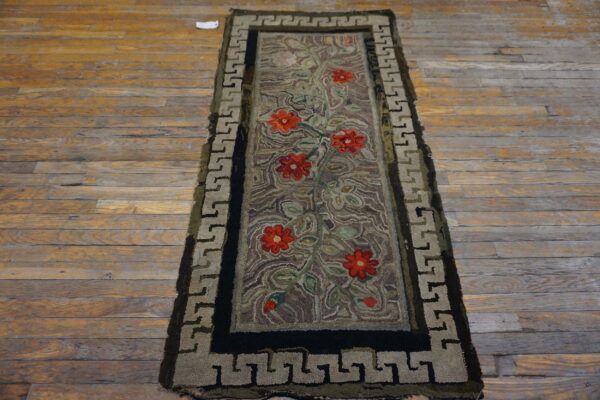 Textured runner with red florals, green vines, and a taupe greek key border lying on distressed wood planks.