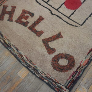 Textured beige rug displays rust lettering and a colorful border on rustic gray wood flooring.