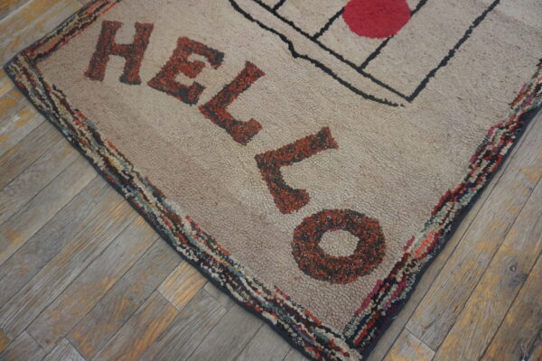 Textured beige rug displays rust lettering and a colorful border on rustic gray wood flooring.
