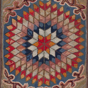 Textured rug featuring a central geometric star medallion and ornate scrolling border in blue, red, and tan.