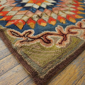 High-pile rug corner featuring a blue, orange, and tan medallion inside a moss green, scrolled border.