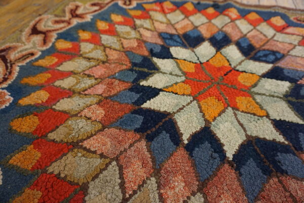 A highly textured, multi-color rug detail showing a geometric star pattern on a navy blue ground.