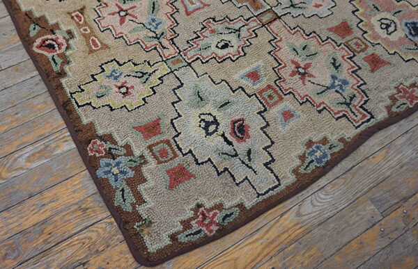 Muted beige rug with multicolor geometric floral designs and looped texture lies on distressed wood planks.