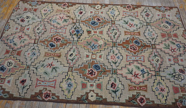 Beige rug with multicolored geometric and stylized floral motifs in brown, blue, and pink on plank wood flooring.