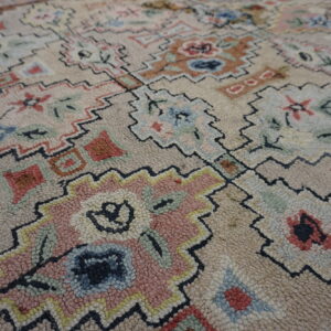 Textured, light beige rug featuring abstract floral and geometric designs outlined in black zigzags.