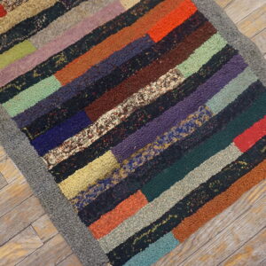 A high-pile patchwork rug features multicolored, solid, and speckled horizontal stripes on wood flooring.