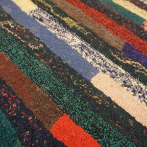 Multicolored, textured rug featuring thick, horizontal blocks of red, teal, brown, purple, and cream.