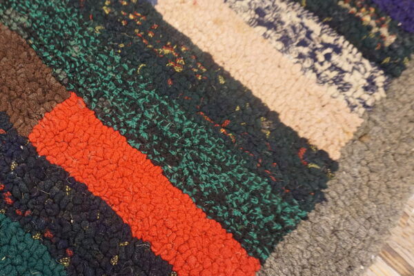 High-pile, chunky textured rug showing diagonal multicolored blocks of deep teal, orange, navy, and tan.