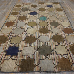 Geometric rug with large colorful eight-pointed stars and striped background on weathered gray wooden planks.