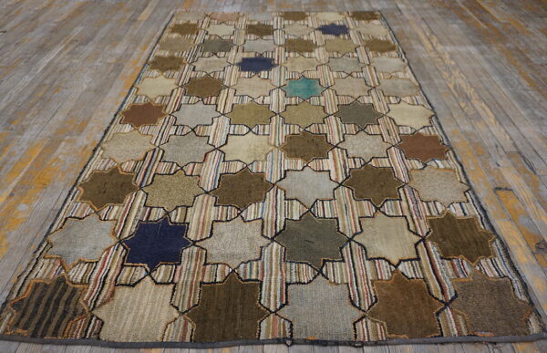 Geometric rug with large colorful eight-pointed stars and striped background on weathered gray wooden planks.