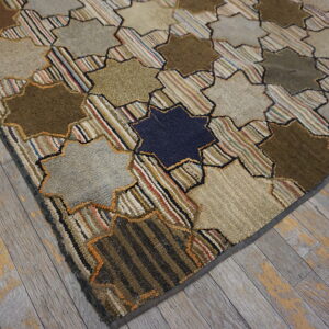 A highly textured, star-patterned rug in browns, tans, and multicolored stripes lies on distressed gray wood flooring.