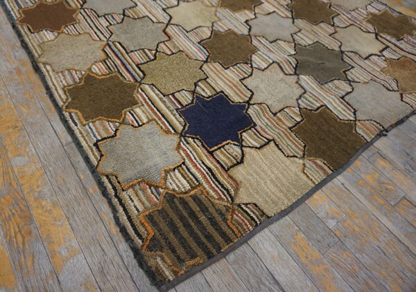 A highly textured, star-patterned rug in browns, tans, and multicolored stripes lies on distressed gray wood flooring.