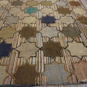 Geometric rug with alternating solid earth-tone stars and striped vertical bands on light wood flooring.