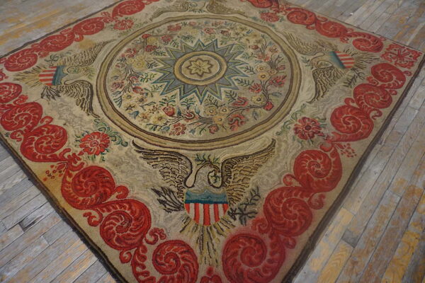 Low-pile beige rug with a circular floral design, red scroll border, and heraldic eagle emblems.