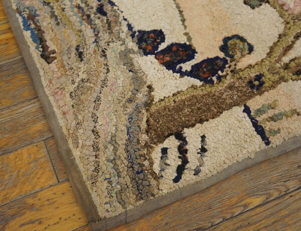 Highly textured hooked rug featuring cream, blue, and brown patterns, viewed close-up on wood flooring.