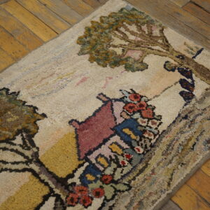Cream hooked rug featuring a colorful house and tree design sits on distressed yellow wood planks.