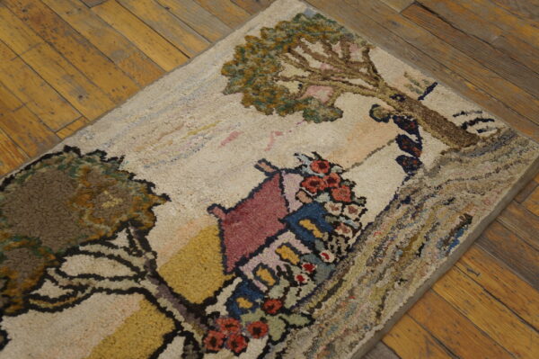 Cream hooked rug featuring a colorful house and tree design sits on distressed yellow wood planks.