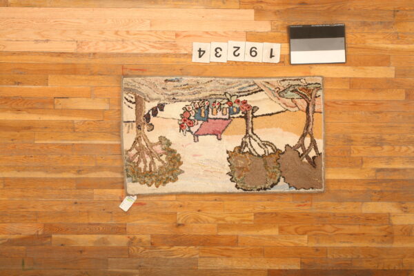 Pictorial hooked rug with trees and figures in earth tones rests on a natural plank wood floor.