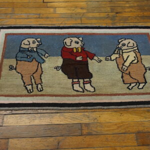 Colorful hooked rug featuring three clothed pigs in blue, red, and tan, resting on distressed wood planks.