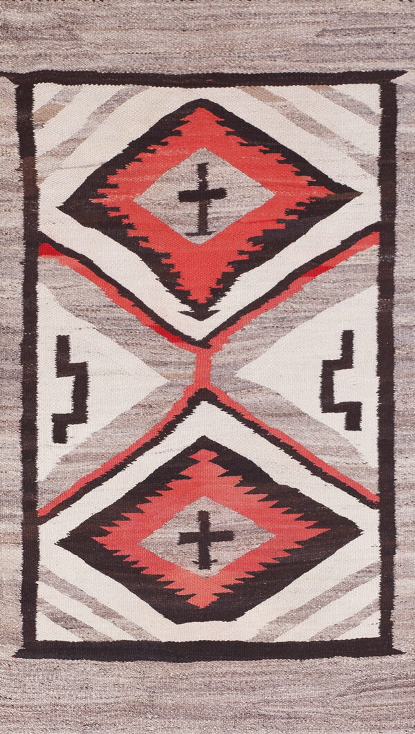 Vertical flatweave rug with stacked geometric diamond patterns in coral red, dark brown, and cream against gray.