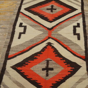 Cream, coral, and dark brown geometric runner rug with cross motifs lying on light plank flooring.